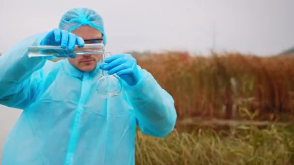 科学家生态学家的工作 人类将试管中的水样倒入瓶中进行进一步的污染研究 生物学家分析水的试验 高质量的4K镜头 — 图库视频影像