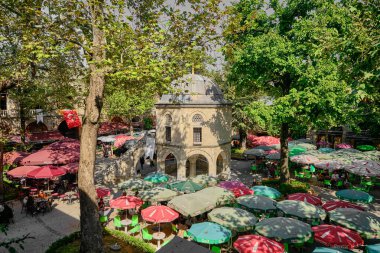 29.03.2021. Bursa. Hindi. Bursa 'daki Kozahan' ın içinde, ahşap ve camdan yapılmış bir masa ve koltuk var. Güneşli bir günde Kozahan 'ın içinde bir mescit var..