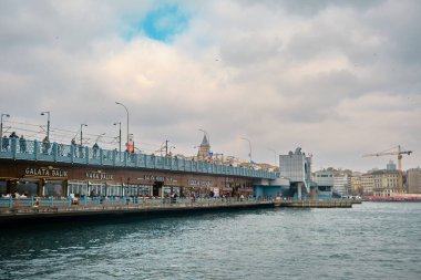 İstanbul 'un iki tarihi yapısı, Galata Köprüsü ve bulutlu gökyüzü arka planına sahip Galata Kulesi. 03.03.2021 İstanbul Türkiye.