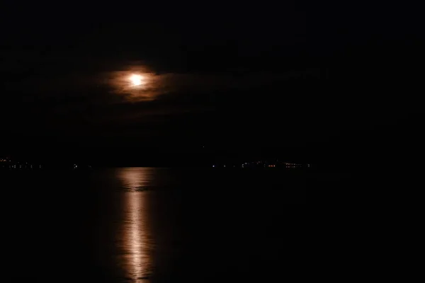 Full moon, moon reflection on lake of iznik lake at middle of the night during bright night.