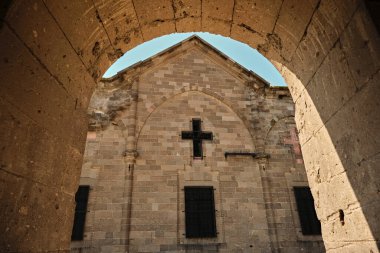 Kemer ve kilise arka planı, mimari ayrıntılar ve taş duvar ve arka planda haç. Kutsal haçın Hıristiyan sembolü.
