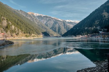 Nature view, long lake, snow at mountain peak and its reflection on water.