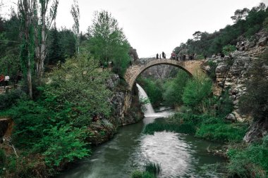 02.05.2022. Usak. Türkiye Karahalli 'deki Cilandiras Köprüsü, antik köprü ve şelalenin uzun pozlu ve seçici odak fotoğrafı Clandras Koprusu