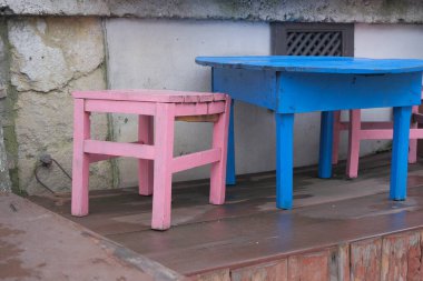 Şirin kafe, küçük pembe sandalyeler ve şirin kafede ahşap zemin üzerinde sarı masa..