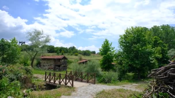 古い木造の小屋と緑の芝生 コテージ 木製の橋と曇りの空の背景を持つ田舎道 4Kビデオ — ストック動画