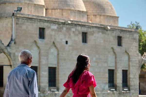 Old man and young beautiful woden in red, walking in Sanliurfa, Turkey.07.12.2022