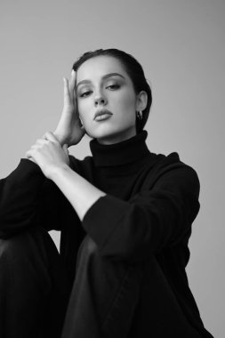 Genç fantastik modelin siyah beyaz fotoğrafı. Stüdyo. Avrupalı bir tip, yakışıklı dudaklar, güzel gözler. Beyaz arka plan. Duygusallık. Minimalist ve şık. Moda. Kozmetik reklamı için iyi..