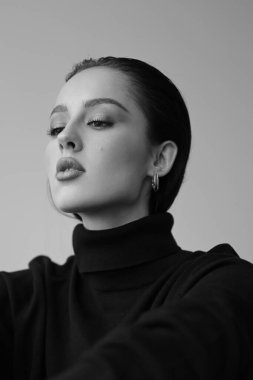 Genç fantastik modelin siyah beyaz fotoğrafı. Stüdyo. Avrupalı bir tip, yakışıklı dudaklar, güzel gözler. Beyaz arka plan. Duygusallık. Minimalist ve şık. Moda. Kozmetik reklamı için iyi..