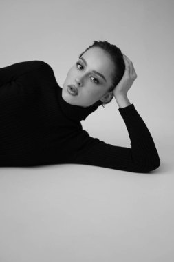 Genç fantastik modelin siyah beyaz fotoğrafı. Stüdyo. Avrupalı bir tip, yakışıklı dudaklar, güzel gözler. Beyaz arka plan. Duygusallık. Minimalist ve şık. Moda. Kozmetik reklamı için iyi..