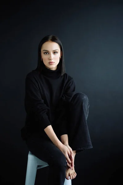 Genç fantastik modelin zarif fotoğrafları. Stüdyo. Avrupalı bir tip, yakışıklı dudaklar, güzel gözler. Siyah arka plan. Siyah kıyafetler. Duygusallık. Minimalizm. Çok şık. Kozmetik reklamı için iyi.
