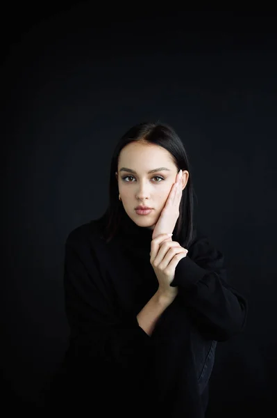 Genç fantastik modelin zarif fotoğrafları. Stüdyo. Avrupalı bir tip, yakışıklı dudaklar, güzel gözler. Siyah arka plan. Siyah kıyafetler. Duygusallık. Minimalizm. Çok şık. Kozmetik reklamı için iyi.
