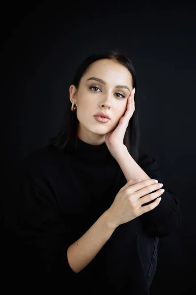 Genç fantastik modelin zarif fotoğrafları. Stüdyo. Avrupalı bir tip, yakışıklı dudaklar, güzel gözler. Siyah arka plan. Siyah kıyafetler. Duygusallık. Minimalizm. Çok şık. Kozmetik reklamı için iyi.
