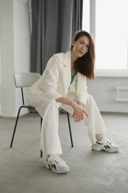 Klasik beyaz takım elbiseli güzel bir bayan. Esmer. Avrupalı. Tarafsız bir arkaplan. Zarif ve seksi. Kadın sorunları ve yaşam tarzı hakkında. Güzellik ve kozmetoloji reklamları için iyi. Sağlıklı ve akıllı yaşam tarzı.