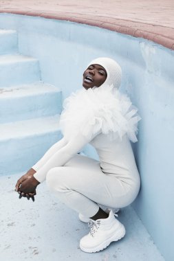 Uzaylı. Mükemmel vücutlu Afrikalı güzel bir model. Kaslı, çikolata tenli. Alışılmadık kıyafetler. Arka planda su, doğal renkler. Yaz manzarası. Sakin ve dengeli