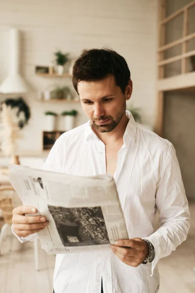 stock image European man in his flat. Sitting in the living room. Bronze skin. Dark eyes and hair. Beard. Light colored interior. Casual clothes style. Weekend at home. Domestic atmosphere. Cosiness and comfort