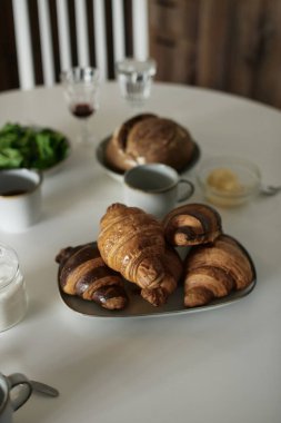 Beyaz masada lezzetli ve sağlıklı bir kahvaltı. Kruvasan, süt, bal, ekmek. Avrupa yaşam tarzı. Akdeniz yemekleri. Şık yemekler. Modern iç mekan. Taze fırın. Ispanak. Çay ve kahve. Taze meyve suyu