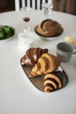 Beyaz masada lezzetli ve sağlıklı bir kahvaltı. Kruvasan, süt, bal, ekmek. Avrupa yaşam tarzı. Akdeniz yemekleri. Şık yemekler. Modern iç mekan. Taze fırın. Ispanak. Çay ve kahve. Taze meyve suyu