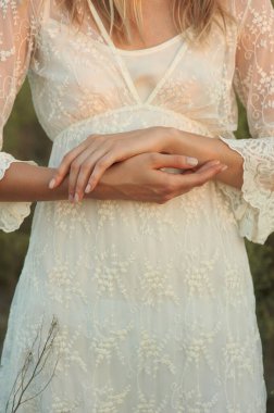 Beyaz romantik elbiseli, yaz mevsiminde muhteşem bir genç kadın. Sarı çimenler, mavi gökyüzü. Güneşli bir gün. Büyük güzel gözleri ve güzel dudakları olan sarışın bir manken. Sakin ve dengeli. Şık görünüş.  