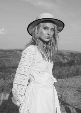 Yaz tarlasında beyaz romantik elbiseler içinde muhteşem genç bir kadın. Güneşli bir gün. Büyük güzel gözleri ve güzel dudakları olan sarışın bir manken. Sakin ve dengeli. Modaya uygun. Siyah ve beyaz. Duygusal Portre.