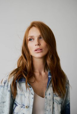 Kızıl saçlı, mavi gözlü ve uzun dalgalı kızıl saçlı güzel bir manken. Şehvetli ve çekici bir kadın. Çiller. Tarafsız bir arkaplan. Mükemmel kalite. Yumuşak ışık. Kot ceket. Güzel kirpikleri, büyük dudakları, güzel gözleri var.