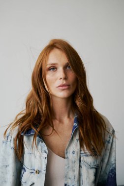 Kızıl saçlı, mavi gözlü ve uzun dalgalı kızıl saçlı güzel bir manken. Şehvetli ve çekici bir kadın. Çiller. Tarafsız bir arkaplan. Mükemmel kalite. Yumuşak ışık. Kot ceket. Güzel kirpikleri, büyük dudakları, güzel gözleri var.