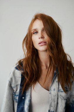 Kızıl saçlı, mavi gözlü ve uzun dalgalı kızıl saçlı güzel bir manken. Şehvetli ve çekici bir kadın. Çiller. Tarafsız bir arkaplan. Mükemmel kalite. Yumuşak ışık. Kot ceket. Güzel kirpikleri, büyük dudakları, güzel gözleri var.