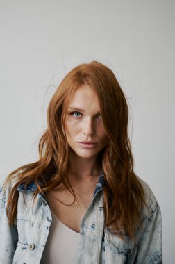 Kızıl saçlı, mavi gözlü ve uzun dalgalı kızıl saçlı güzel bir manken. Şehvetli ve çekici bir kadın. Çiller. Tarafsız bir arkaplan. Mükemmel kalite. Yumuşak ışık. Kot ceket. Güzel kirpikleri, büyük dudakları, güzel gözleri var.
