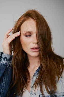 Kızıl saçlı, mavi gözlü ve uzun dalgalı kızıl saçlı güzel bir manken. Şehvetli ve çekici bir kadın. Çiller. Tarafsız bir arkaplan. Mükemmel kalite. Yumuşak ışık. Kot ceket. Güzel kirpikleri, büyük dudakları, güzel gözleri var.