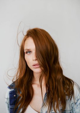 Kızıl saçlı, mavi gözlü ve uzun dalgalı kızıl saçlı güzel bir manken. Şehvetli ve çekici bir kadın. Çiller. Tarafsız bir arkaplan. Mükemmel kalite. Yumuşak ışık. Kot ceket. Güzel kirpikleri, büyük dudakları, güzel gözleri var.