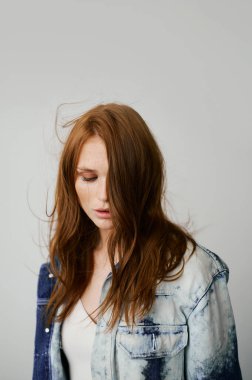 Kızıl saçlı, mavi gözlü ve uzun dalgalı kızıl saçlı güzel bir manken. Şehvetli ve çekici bir kadın. Çiller. Tarafsız bir arkaplan. Mükemmel kalite. Yumuşak ışık. Kot ceket. Güzel kirpikleri, büyük dudakları, güzel gözleri var.