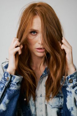 Kızıl saçlı, mavi gözlü ve uzun dalgalı kızıl saçlı güzel bir manken. Şehvetli ve çekici bir kadın. Çiller. Tarafsız bir arkaplan. Mükemmel kalite. Yumuşak ışık. Kot ceket. Güzel kirpikleri, büyük dudakları, güzel gözleri var.