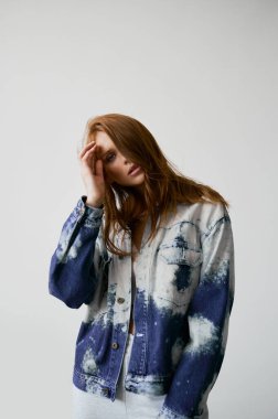 Kızıl saçlı, mavi gözlü ve uzun dalgalı kızıl saçlı güzel bir manken. Şehvetli ve çekici bir kadın. Çiller. Tarafsız bir arkaplan. Mükemmel kalite. Yumuşak ışık. Kot ceket. Güzel kirpikleri, büyük dudakları, güzel gözleri var.