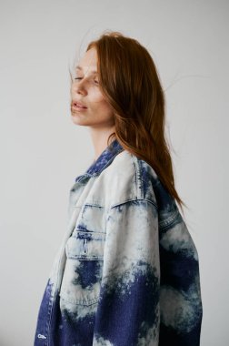 Kızıl saçlı, mavi gözlü ve uzun dalgalı kızıl saçlı güzel bir manken. Şehvetli ve çekici bir kadın. Çiller. Tarafsız bir arkaplan. Mükemmel kalite. Yumuşak ışık. Kot ceket. Güzel kirpikleri, büyük dudakları, güzel gözleri var.