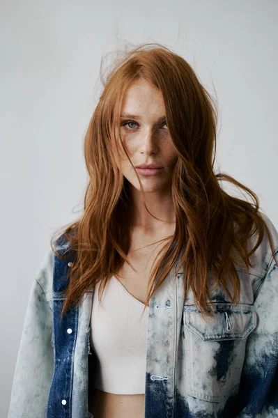 Nice model with red hair, blue eyes and long wavy red hair. Sensual attractive woman. Freckles. Neutral background. Excellent quality. Soft light. Jeans jacket. Nice lashes, big lips, beautiful eyes