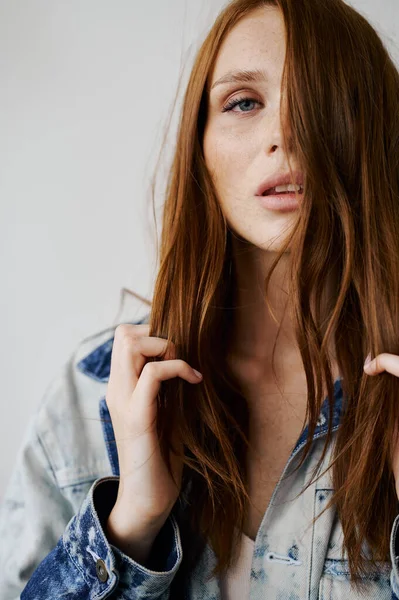 Kızıl saçlı, mavi gözlü ve uzun dalgalı kızıl saçlı güzel bir manken. Şehvetli ve çekici bir kadın. Çiller. Tarafsız bir arkaplan. Mükemmel kalite. Yumuşak ışık. Kot ceket. Güzel kirpikleri, büyük dudakları, güzel gözleri var.