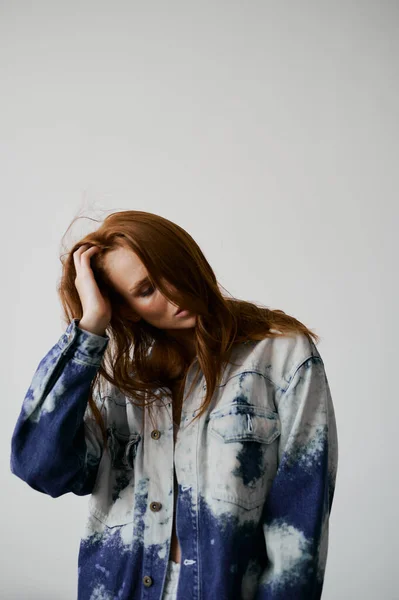 Nice model with red hair, blue eyes and long wavy red hair. Sensual attractive woman. Freckles. Neutral background. Excellent quality. Soft light. Jean jacket. Nice lashes, big lips, beautiful eyes