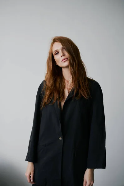 Stock image Beauty portrait of young pretty redhead girl with freckles and long wavy hair in black pajama on white background. Beautiful eyes, nice lips. Natural and healthy look. Perfect eyebrows and lashes.