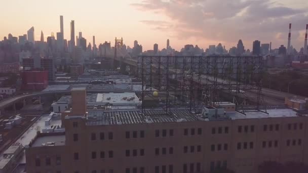 マンハッタンのスカイラインを望むクイーンズボロの高架鉄道線路上を走るニューヨークの地下鉄の空中日没時 — ストック動画