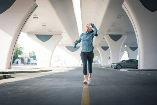 Asian Woman Jogging City Car Park Urban Area Wiping Away — Zdjęcie stockowe
