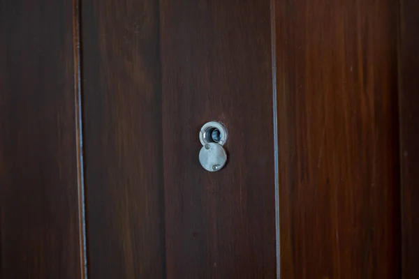 closeup eye door on wood background, peephole