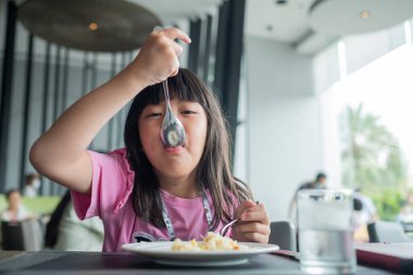 Çocuk yemek yiyor, eğleniyor, kahvaltı yapıyor.