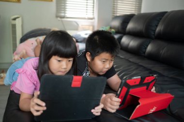 İki çocuk tablet bağımlısı, Asyalı çocuk da araba izliyor.