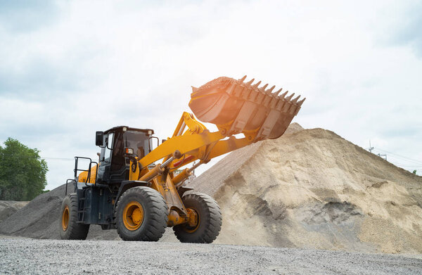 Sand loaders are shoveling rocks into dump trucks