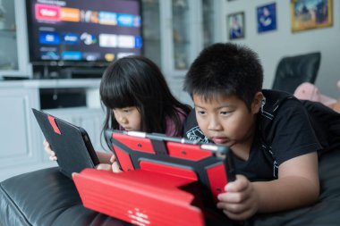 İki çocuk tablet bağımlısı, Asyalı çocuk da araba izliyor.