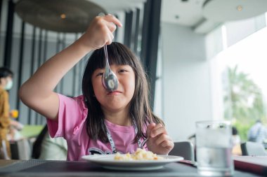 Çocuk yemek yiyor, eğleniyor, kahvaltı yapıyor.
