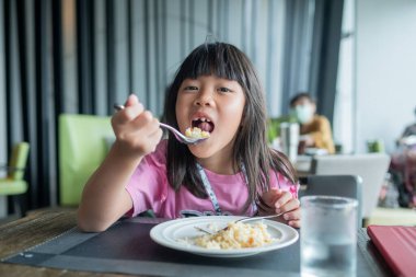 Çocuk yemek yiyor, eğleniyor, kahvaltı yapıyor.