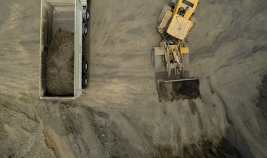 Kum yükleyicileri çöp kamyonlarına taş topluyor.