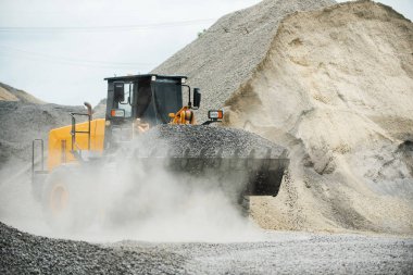 Kum yükleyicileri çöp kamyonlarına taş topluyor.