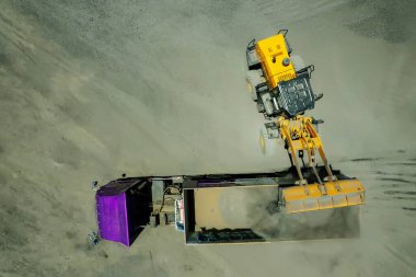 Kum yükleyicileri çöp kamyonlarına taş topluyor.