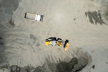 Kum yükleyicileri çöp kamyonlarına taş topluyor.